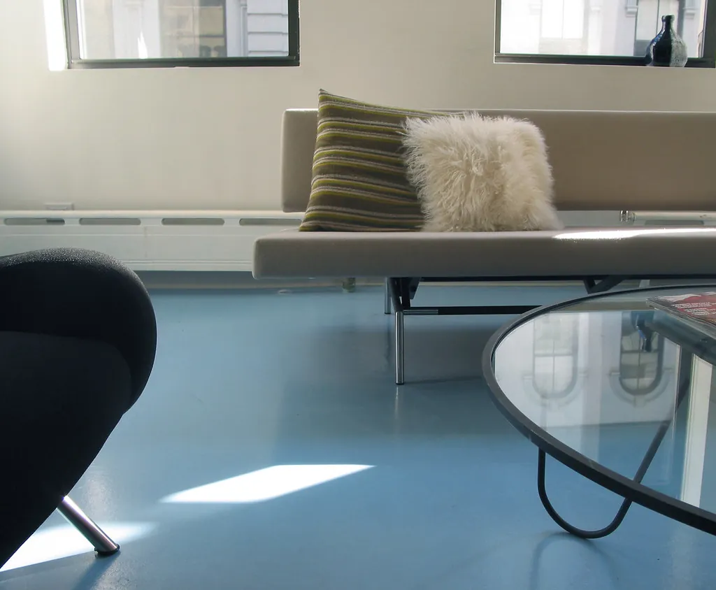 Sala de espera luminosa con sofá, cojines y mesa de cristal